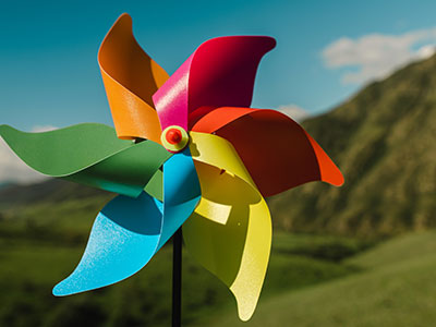 a colourful hand held windmill in front of hills