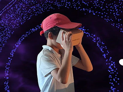 a child wears a VR headset in front of bright lights