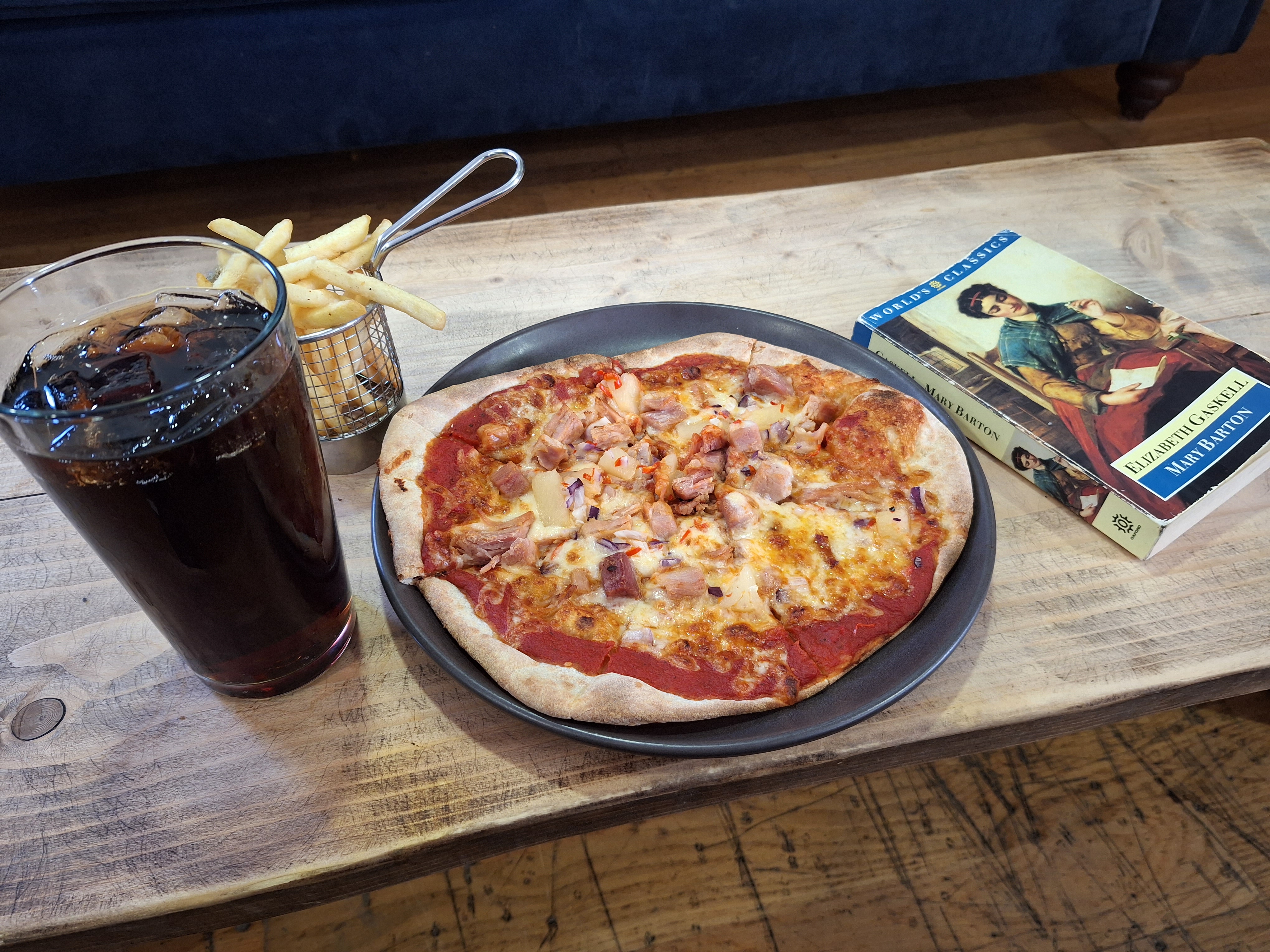 A pizza and fizzy drink on a café table. 