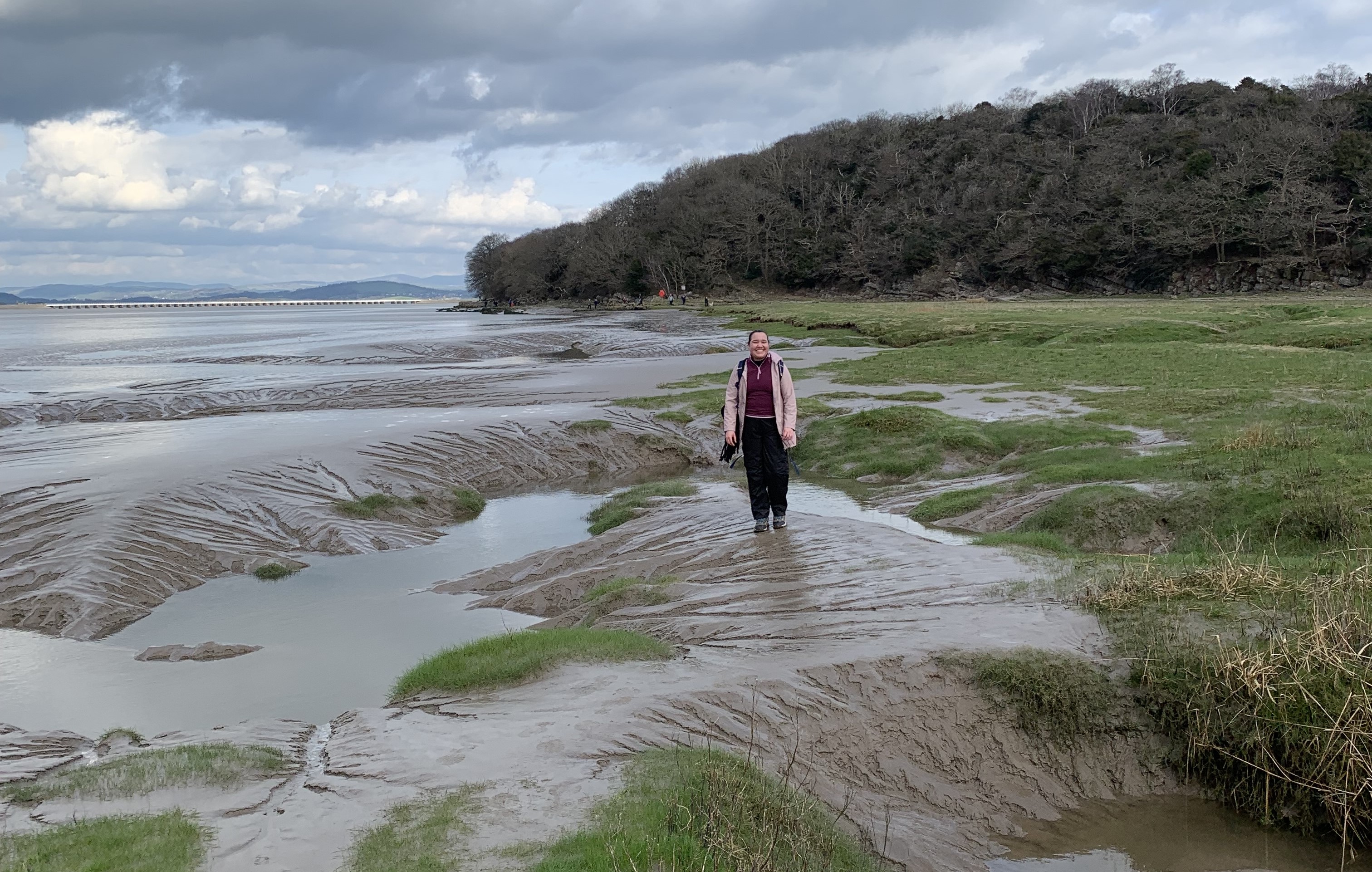 Student Lyea stands smiling on the beachside in Arnside.