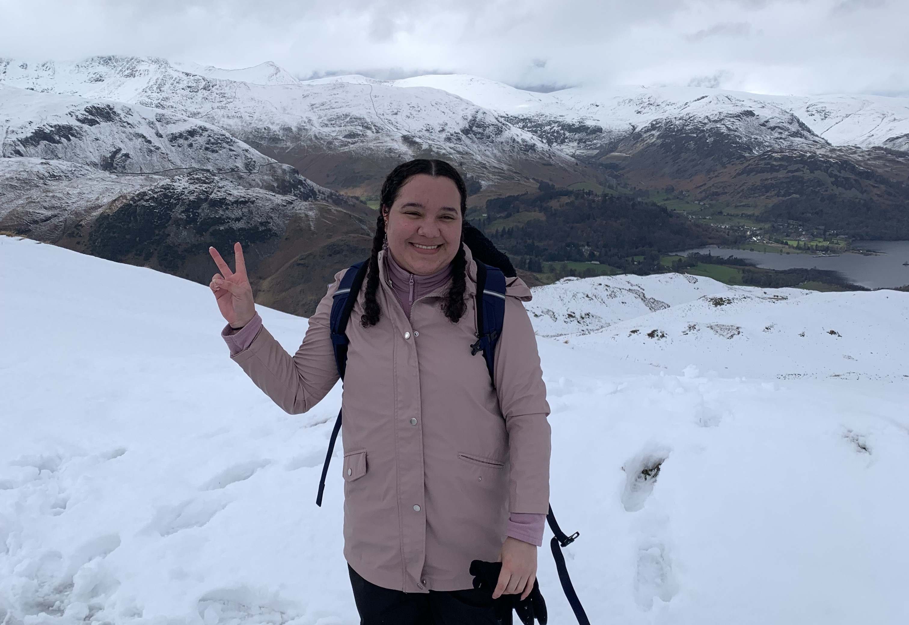 Student Lyea standing on a snowy hill with snowy mountains in the distance.