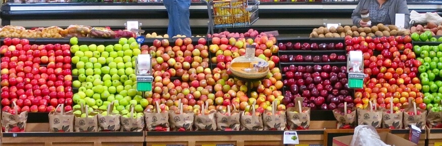A range of green and red apples laid out in the grocery section of a supermarket