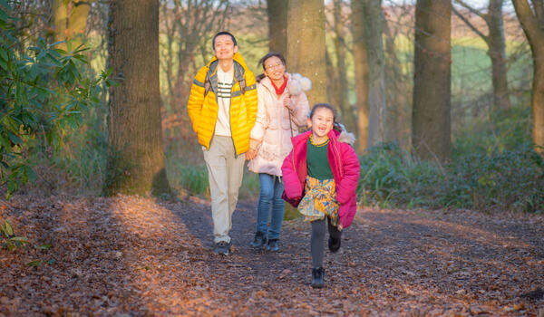 A family runs through the woods on campus