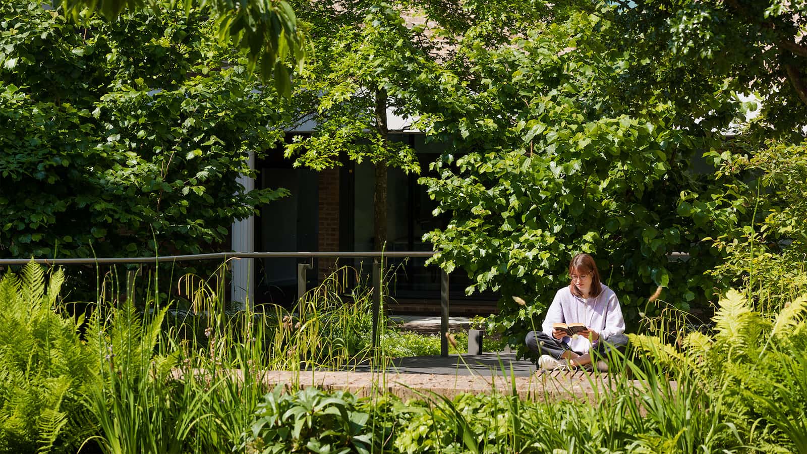 Student reading surrounded by greenery